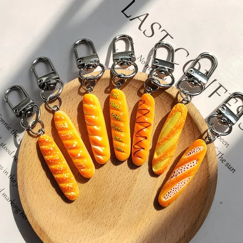Seven resin baguette keychains in different crust patterns on round wood board
