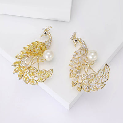 Two colorways of yellow and clear crystal peacock brooches shown side by side.