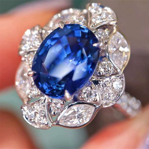 Extreme close-up of oval blue center stone and petal clear halo