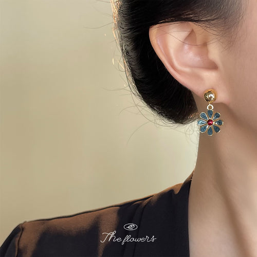 Blue enamel daisy drop earring worn on ear side profile