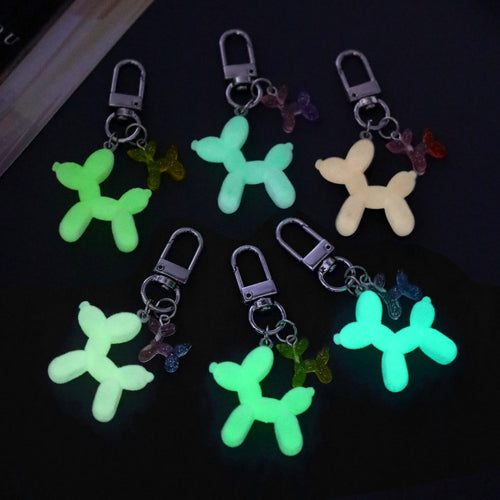 Six balloon dog keychains glowing green under dark light