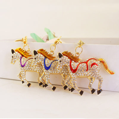 Three rhinestone-covered horses with purple, blue, and red accents stand side by side.