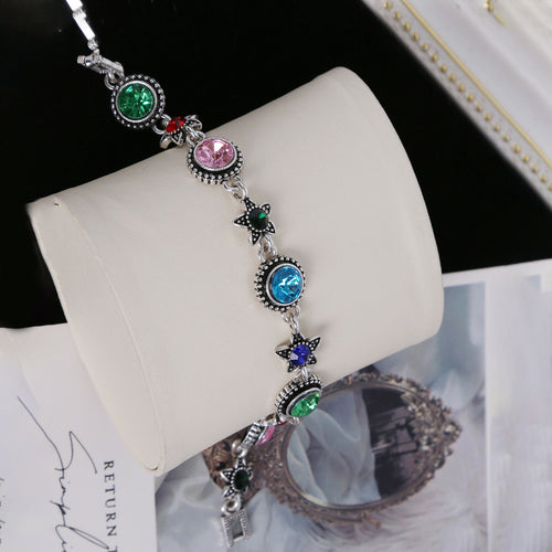 Silver multicolor crystal bracelet on beige jewelry stand with props