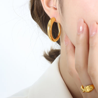 Gold thick hoop earring worn on model ear close-up