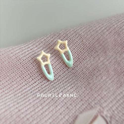 Mint cream star hairpin studs resting on pink knit fabric