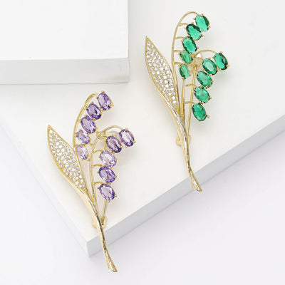 Two colorways of purple and green lily-of-the-valley brooches shown side by side.
