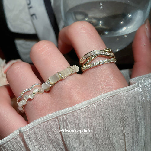 Three gold open rings worn on fingers showing bamboo cat-eye and crystal styles
