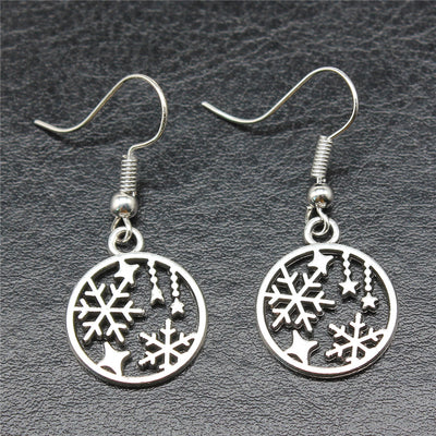 Close view of snowflake and star round drop earrings in silver tone
