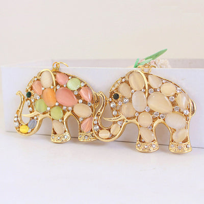 Two gold-tone elephant charms shown in white and multicolor cabochon styles.