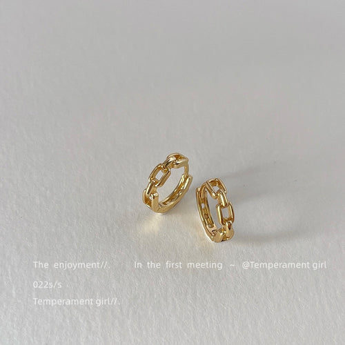 Gold chain link geometric hoops angled on white surface