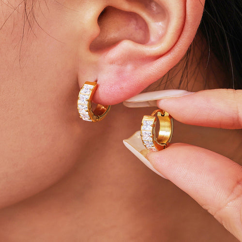 Model wearing one gold pavé hoop while holding the matching earring