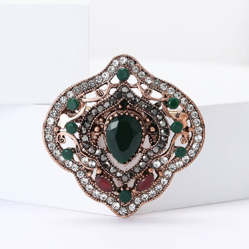 Green center baroque rhinestone brooch angled on white blocks