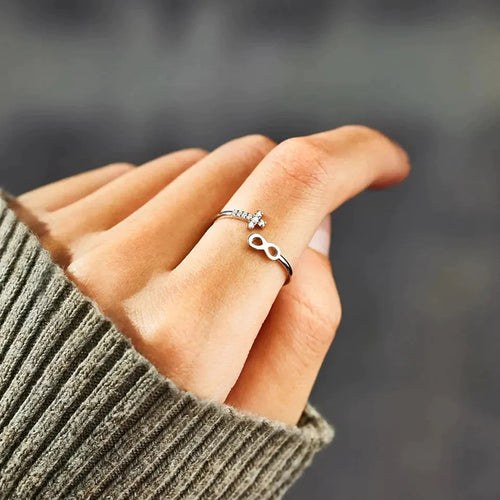 Side view silver open infinity cross ring on finger gray sweater