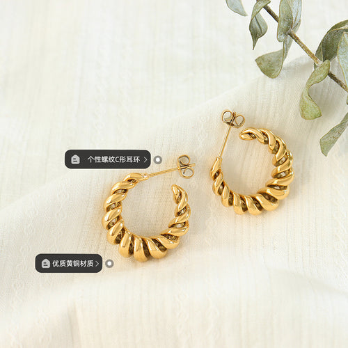 Pair of gold twisted rope C hoops on fabric with brass material tags