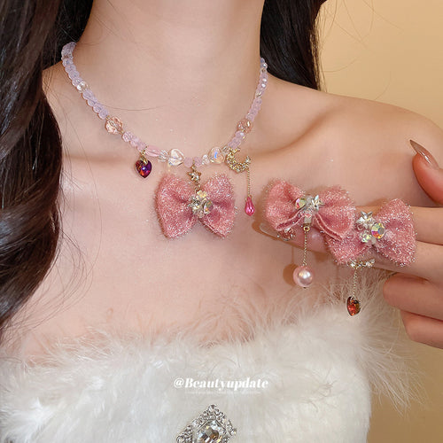 Pink fabric bow necklace worn with matching pink bow studs held nearby