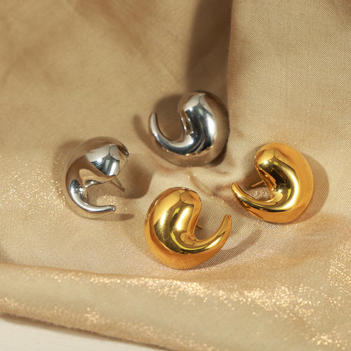 Gold and silver curly teardrop studs on gold fabric