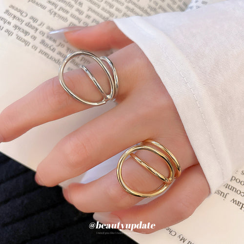 Hand wearing silver and gold geometric double loop open rings