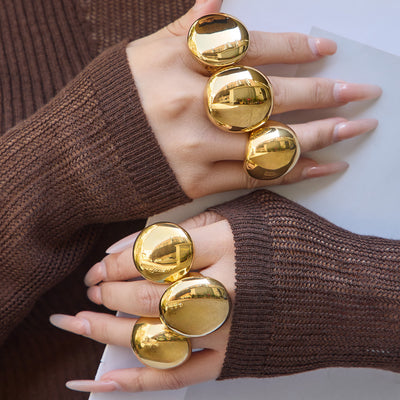 Styled hand view of oversized gold tone domed statement rings in main image 1.