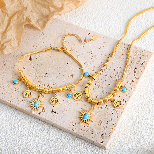 Gold sun turquoise charm necklace and bracelet flat lay on stone slab