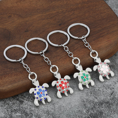 Four silver-tone turtle keychains with blue, red, green, and pink floral accents.