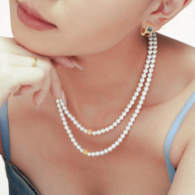 Model wearing double white shell bead necklaces with gold zircon barrel accents