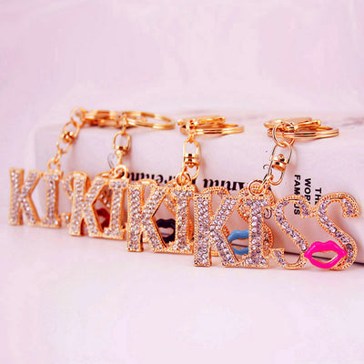Four gold-tone KISS keychains displayed with different colored lip charms.