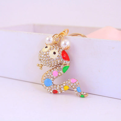 Gold-tone snake ornament with clear rhinestones and colorful accents beside a white box.