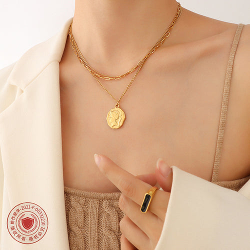 Gold three-layer necklace with coin portrait medallion worn under white blazer