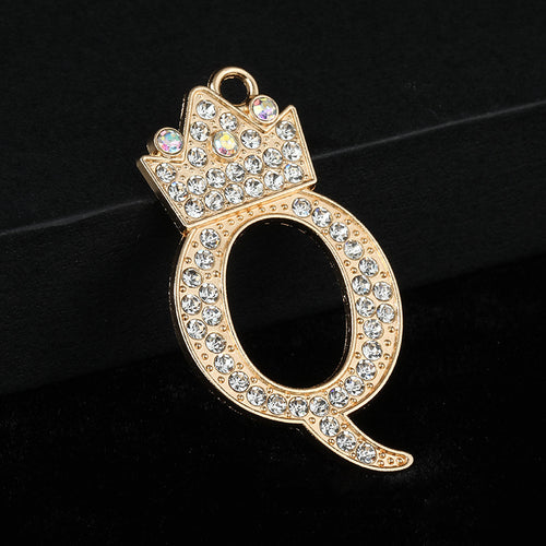 Gold-tone crystal crown initial charm Q with clear rhinestones on a dark background