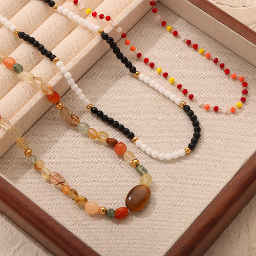 Three beaded necklaces displayed in a wooden tray