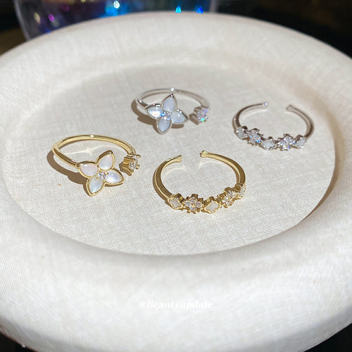 Silver and gold flower open rings and bands on round white dish