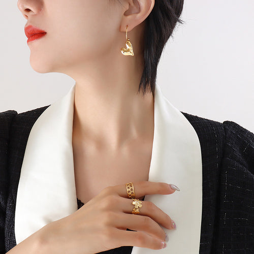 Profile model wearing gold curved wire heart drop earring