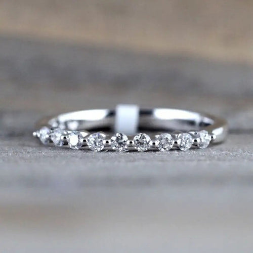 Silver bezel round clear stone thin band ring on wood surface