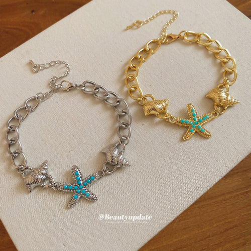 Silver and gold curb chain starfish shell bracelets on linen cloth