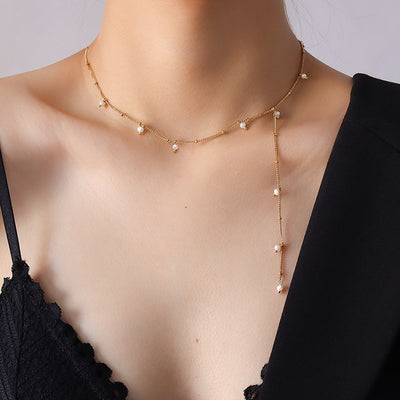 Model wearing gold Y lariat necklace with pearl drops on black lace top