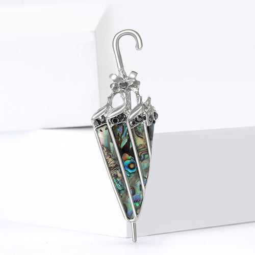 Umbrella brooch upright on white platform showing shell inlays