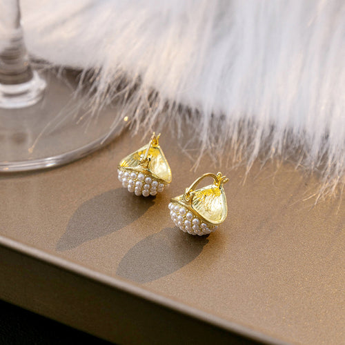Gold seed pearl cluster teardrop hoops on brown tray with white fur