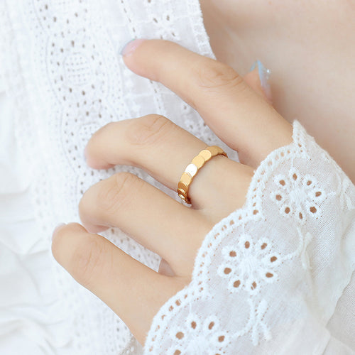 Hand wearing gold scalloped disc band ring with white lace sleeve