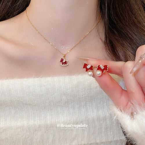 Gold red rocking horse necklace worn with matching pearl drop studs held
