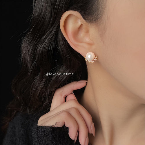 Gold pearl leaf CZ stud worn on ear with hand near face