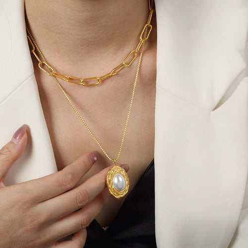 Model wearing gold paperclip and pearl pendant layered necklace