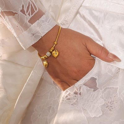 Gold double heart snake chain bracelet on wrist with white lace sleeve
