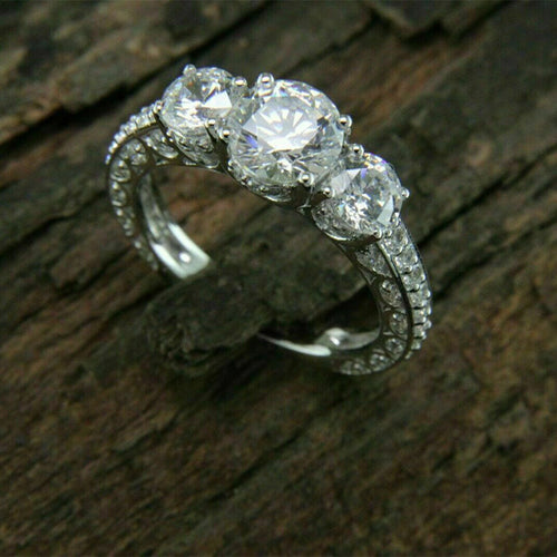 Silver three-stone pave ring another angle on rough wood
