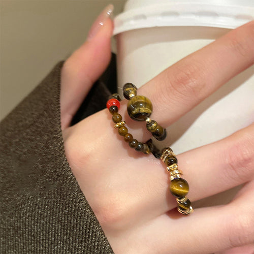 Two tiger eye beaded rings stacked on finger near coffee cup