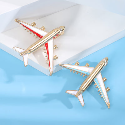Red and blue stripe gold tone enamel airplane brooches on white and blue surface