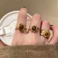 Three Gold Tone Brown Oval Round And Sunburst Stone Ring Designs view 3