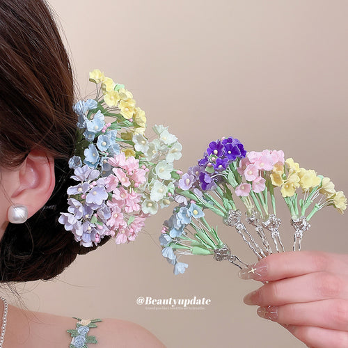 Model wearing mixed pastel flower hair pins with hand holding extra pins