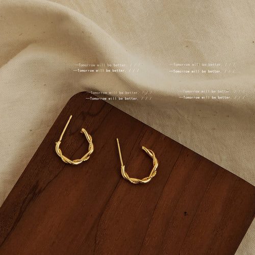 Gold rope-texture open hoops on dark wood board