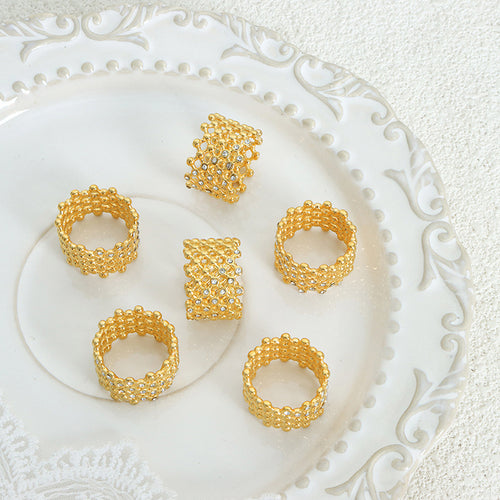 Several gold openwork mesh rings arranged on white ornate plate