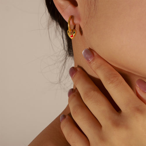 Gold huggie with heart charm worn on ear